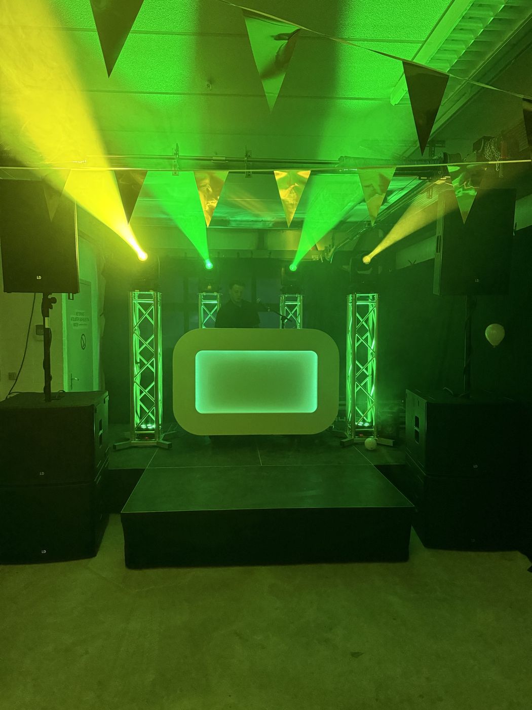 Groene en gele beams, truss en speakers rond de DJ-booth