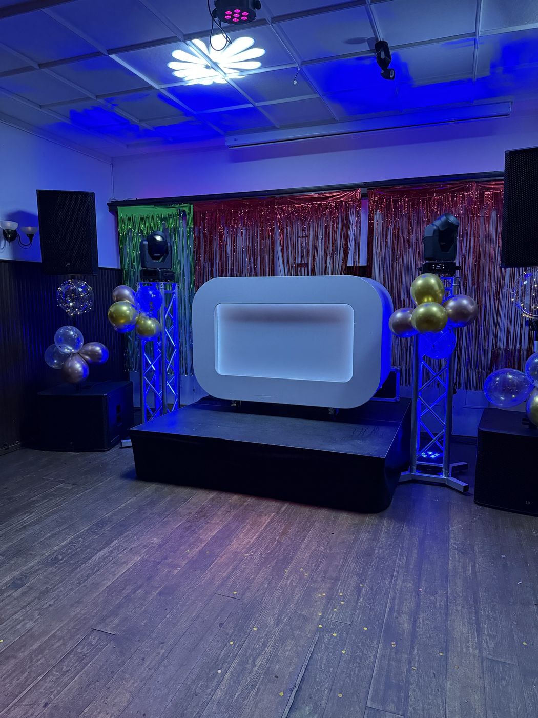 Feestzaal met DJ-booth en goudkleurige ballonnen